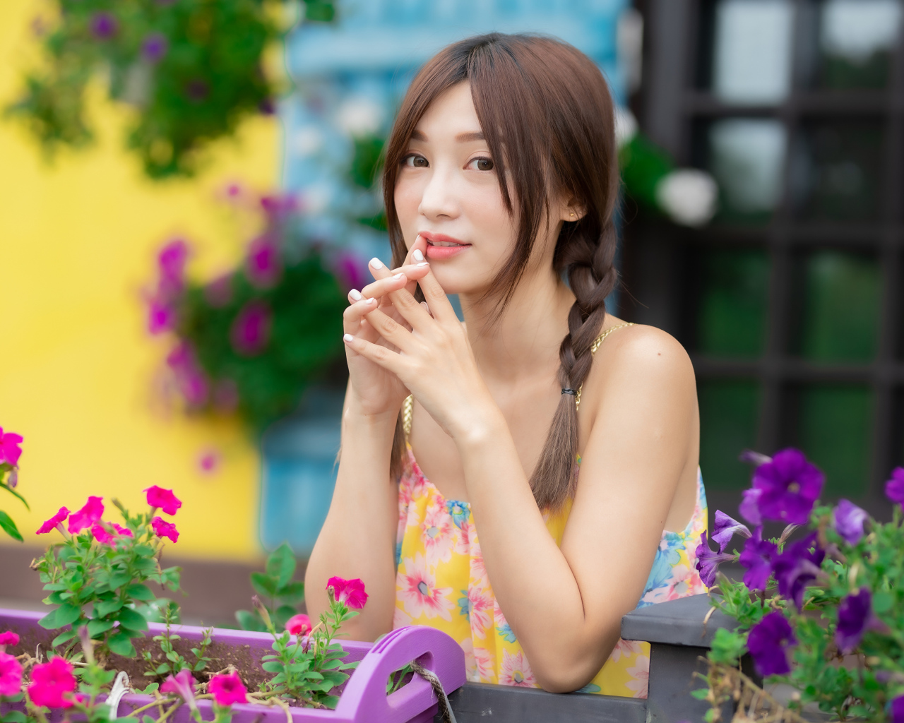 Красивая девушка Азиатка у цветов петунии