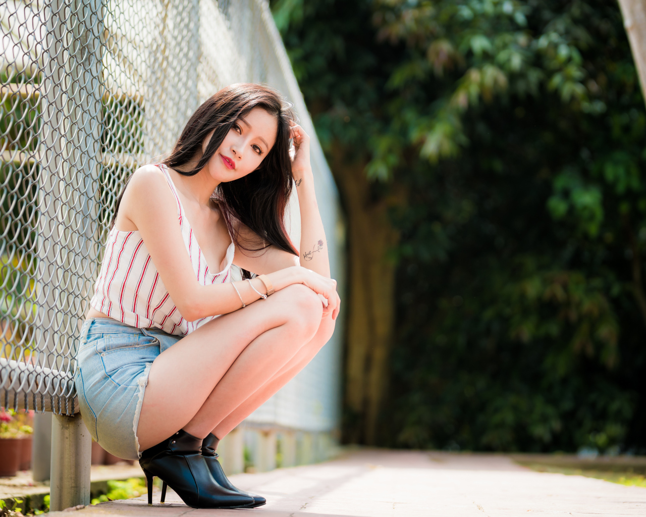 Красивая девушка азиатка сидит у железной сетки