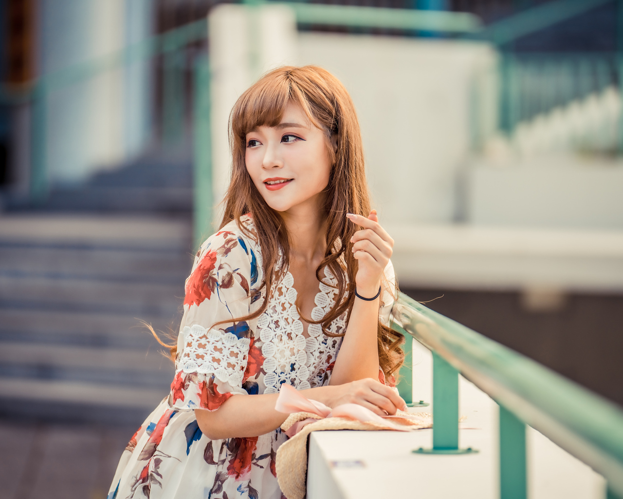 Красивая девушка азиатка стоит у перил 