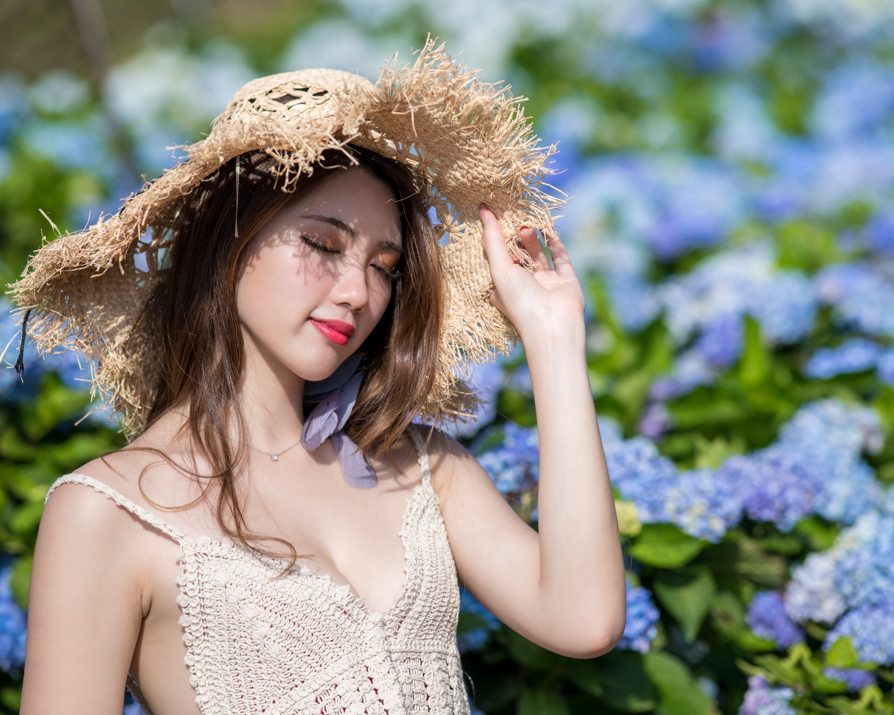 Красивая девушка азиатка с закрытыми глазами на фоне цветов гортензии