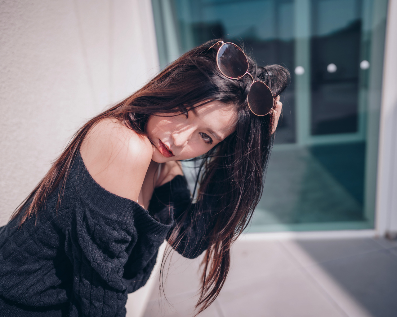 Красивая азиатка в черном свитере с солнечными очками на голове 