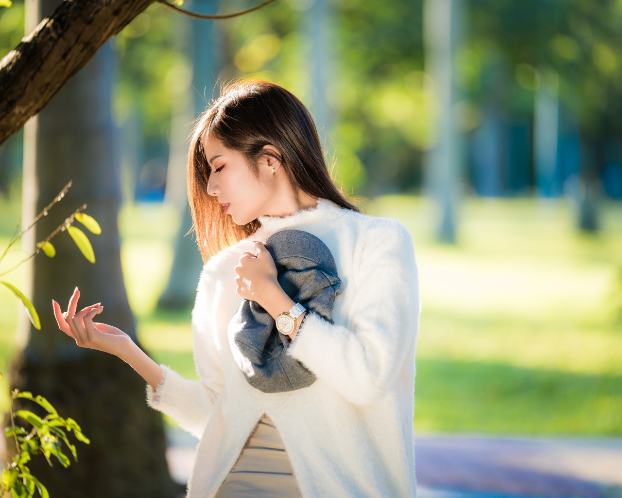 Красивая азиатка в белой кофте в солнечном парке