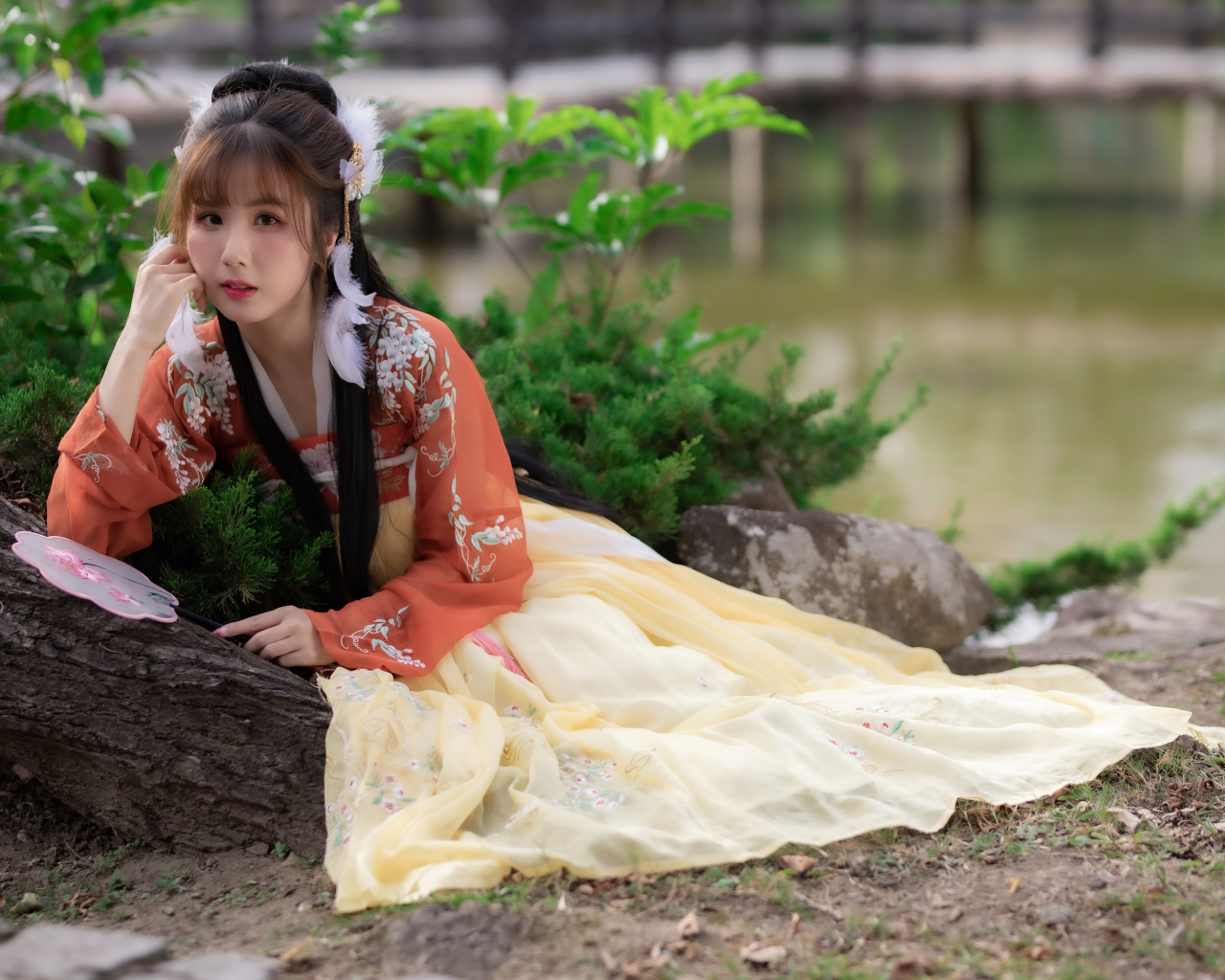 Красивая девушка азиатка сидит на земле у дерева 