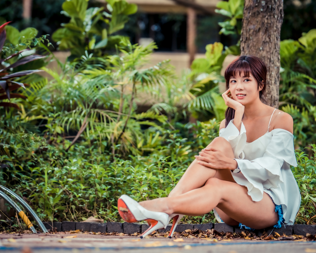 Красивая девушка азиатка сидит на земле в парке 