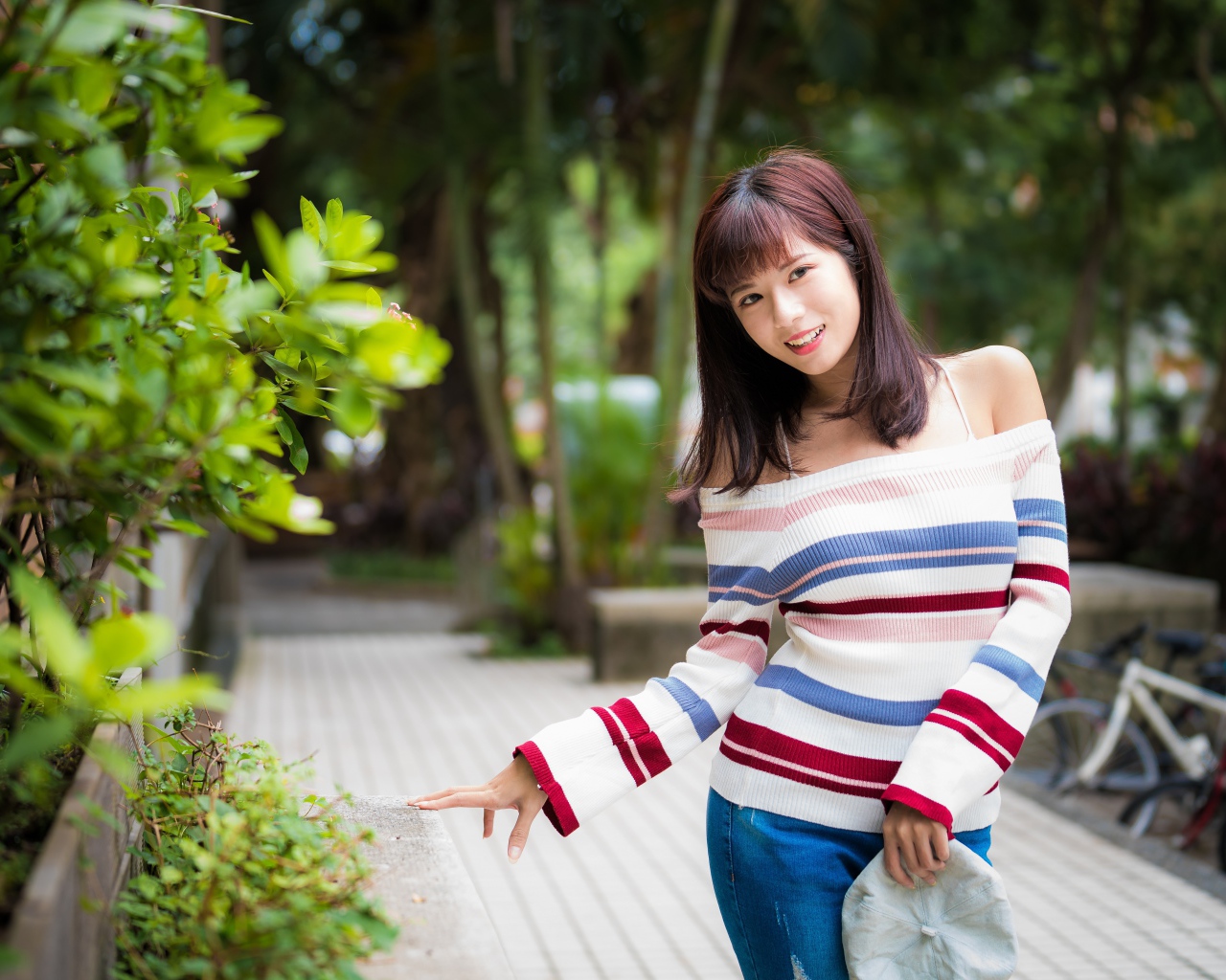 Красивая азиатка в полосатом свитере в парке