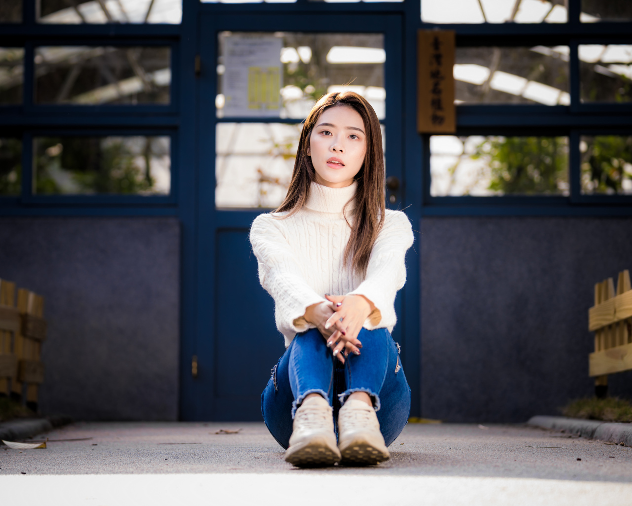 Красивая азиатка в синих джинсах сидит на земле