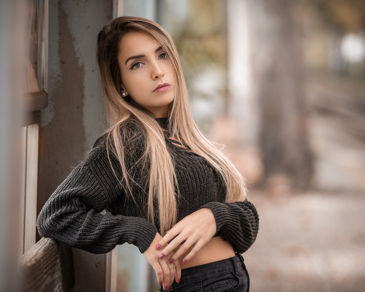 Красивая блондинка в вязаном свитере у стены 
