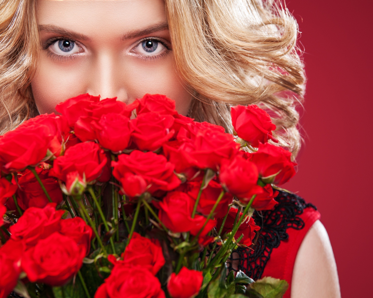 Красивая голубоглазая блондинка с букетом красных роз 