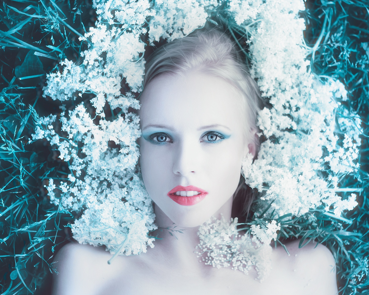 Красивая голубоглазая девушка на траве с белыми цветами