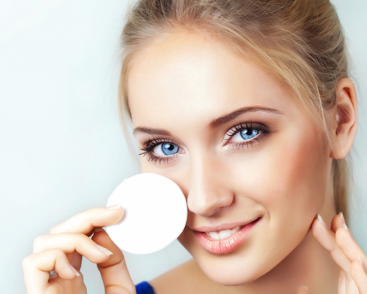 Красивая голубоглазая девушка с ватным диском в руке 