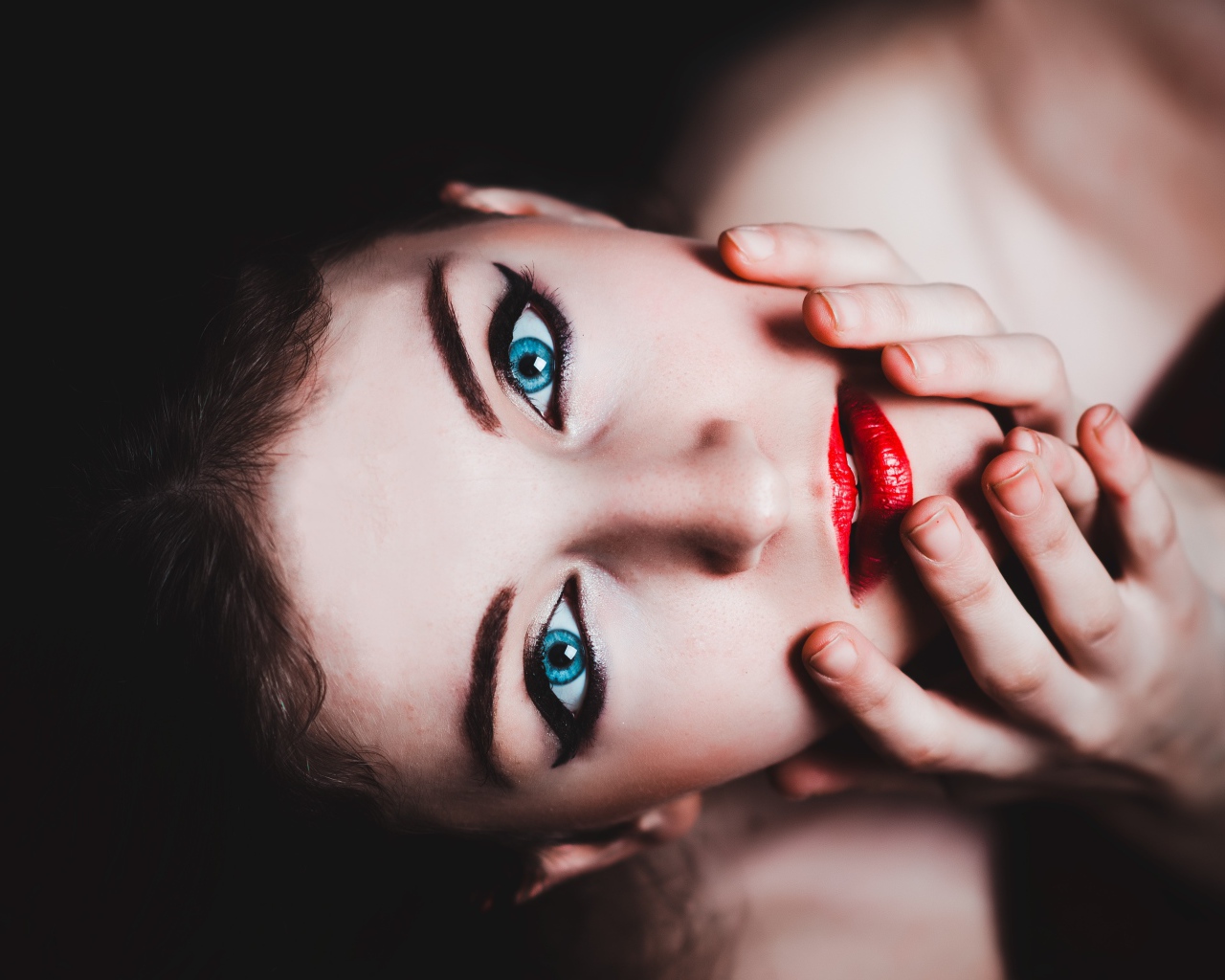 Красивая голубоглазая девушка с красными губами смотрит вверх 