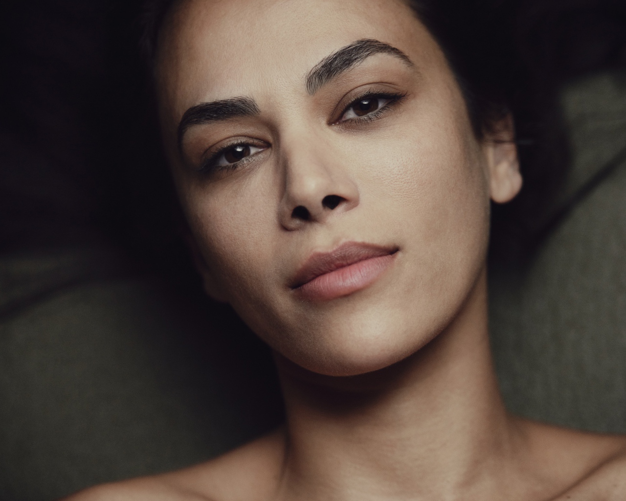 Красивая кареглазая девушка лежит на диване 