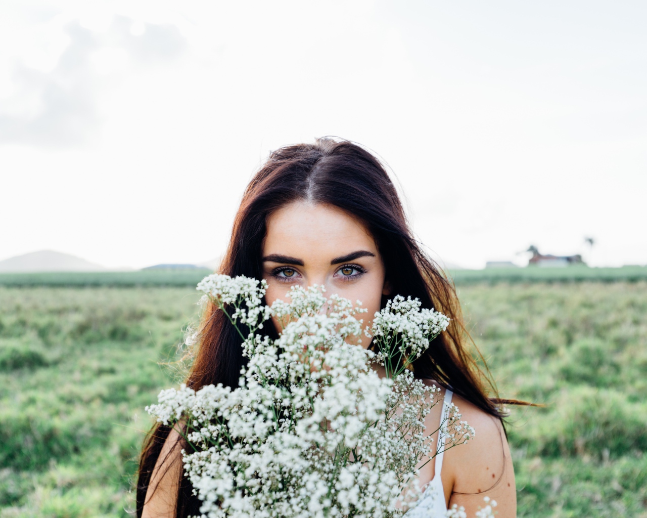Красивая кареглазая девушка с букетом белых полевых цветов 