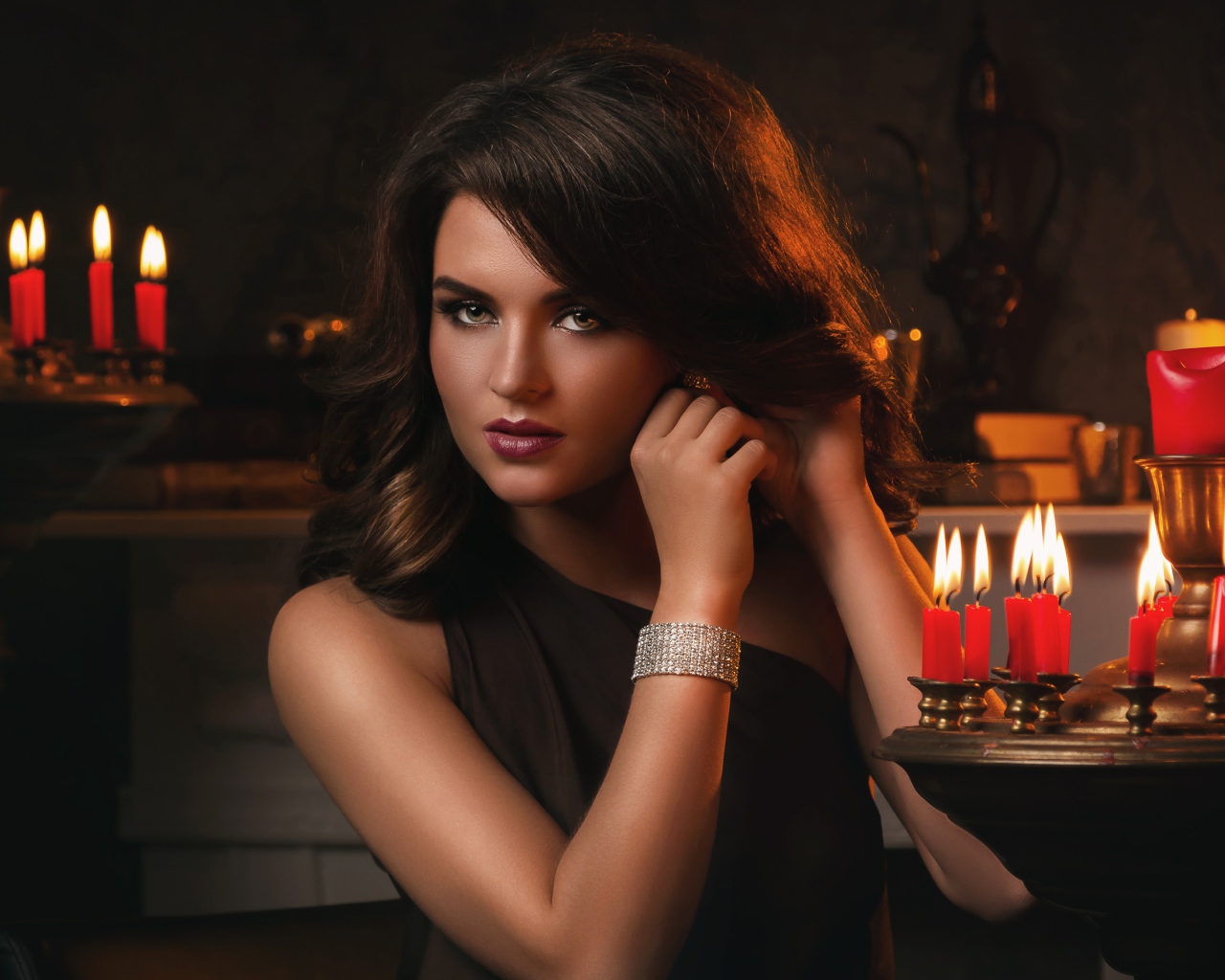 Красивая брюнетка в черном платье и зажженными свечами