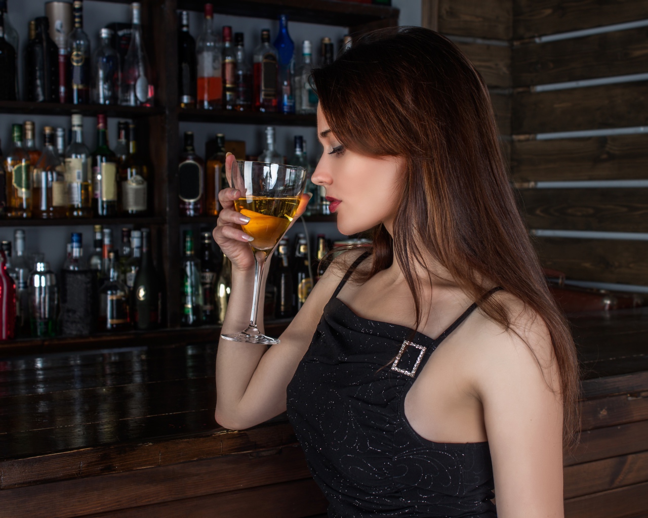 Красивая девушка в черном платье с бокалом в руке 