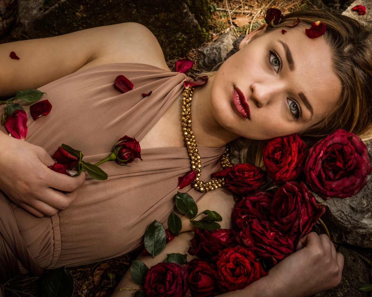 Красивая девушка в платье лежит на земле с розами
