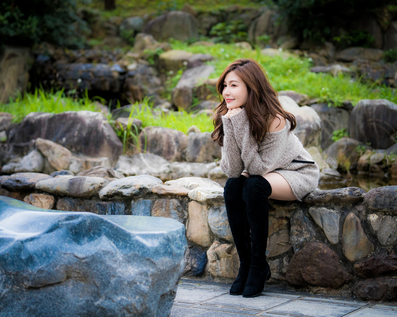 Красивая девушка в кофте сидит у пруда