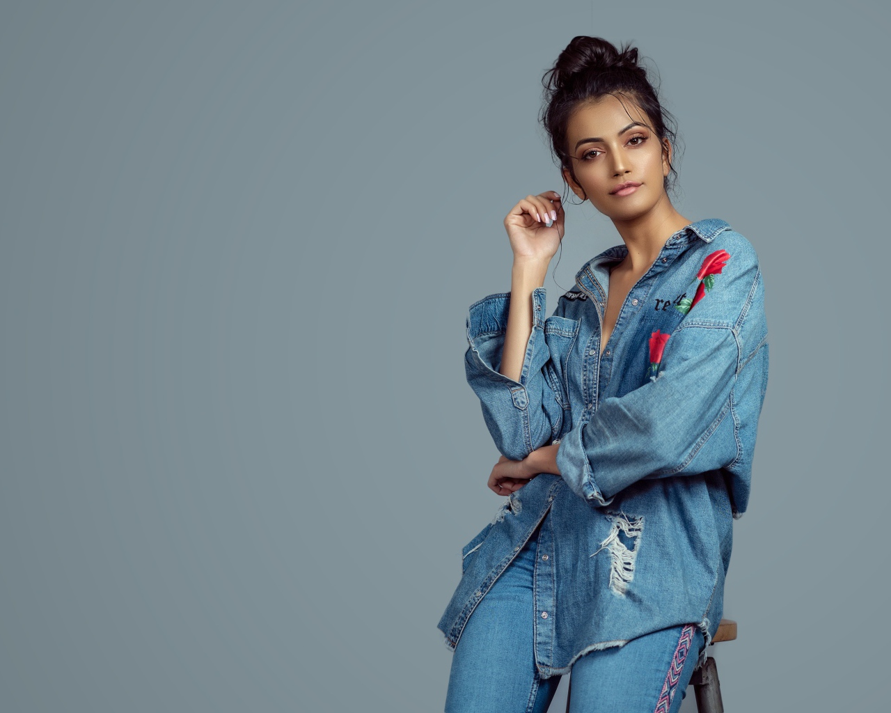 Красивая девушка в джинсовом костюме на сером фоне