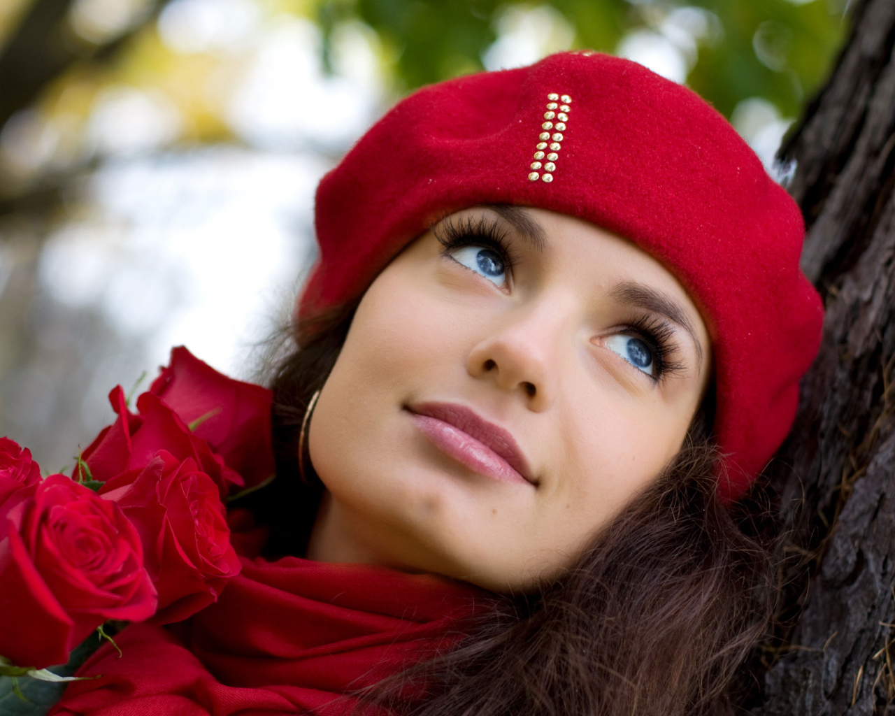 Красивая девушка в красном берете с букетом роз у дерева
