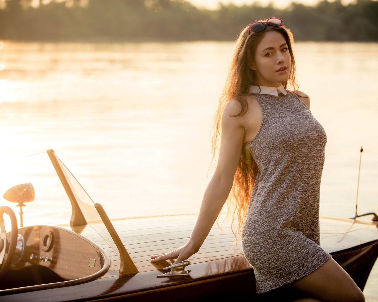 Красивая девушка в коротком платье стоит у катера 