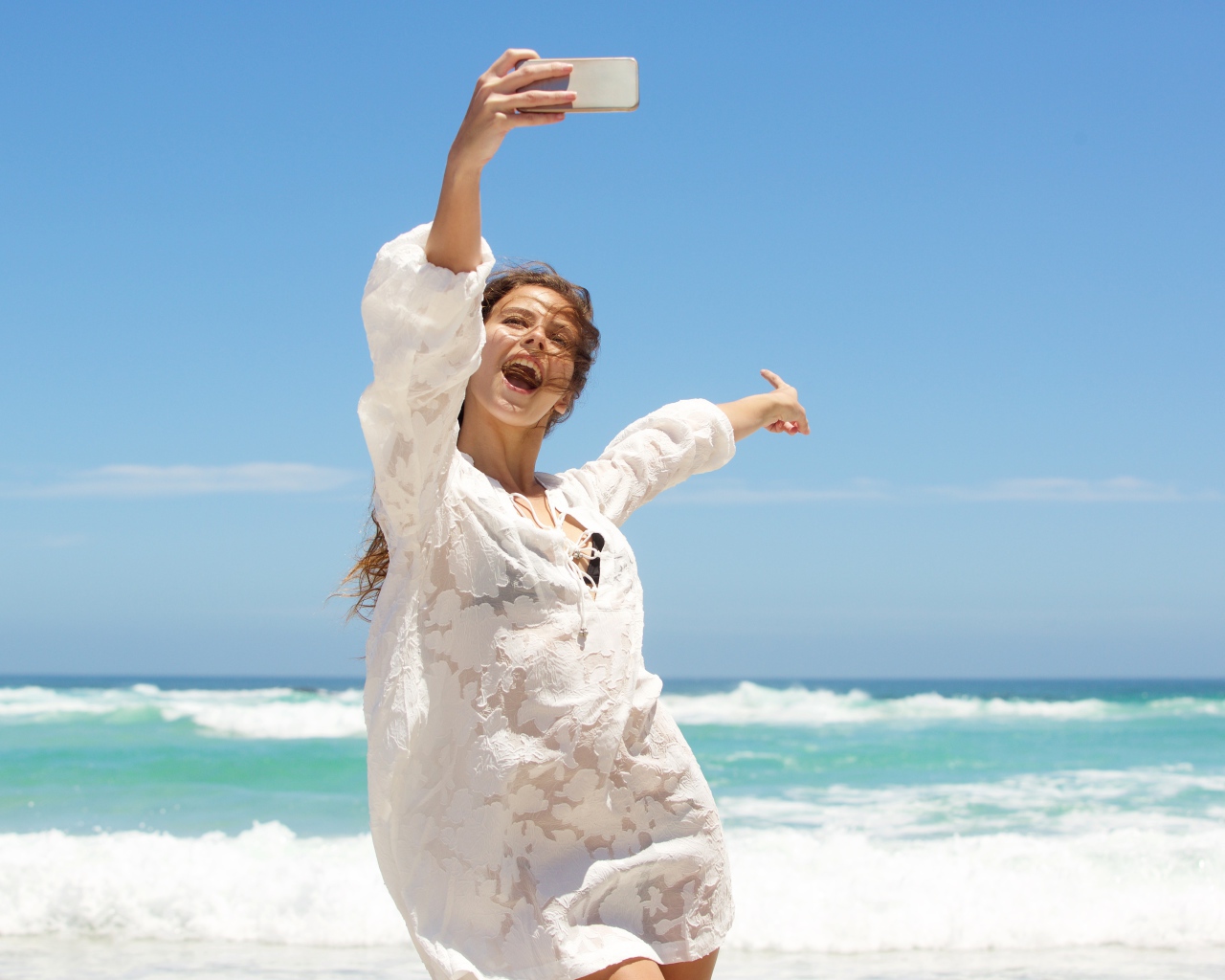 Красивая девушка в белом платье делает селфи на море 