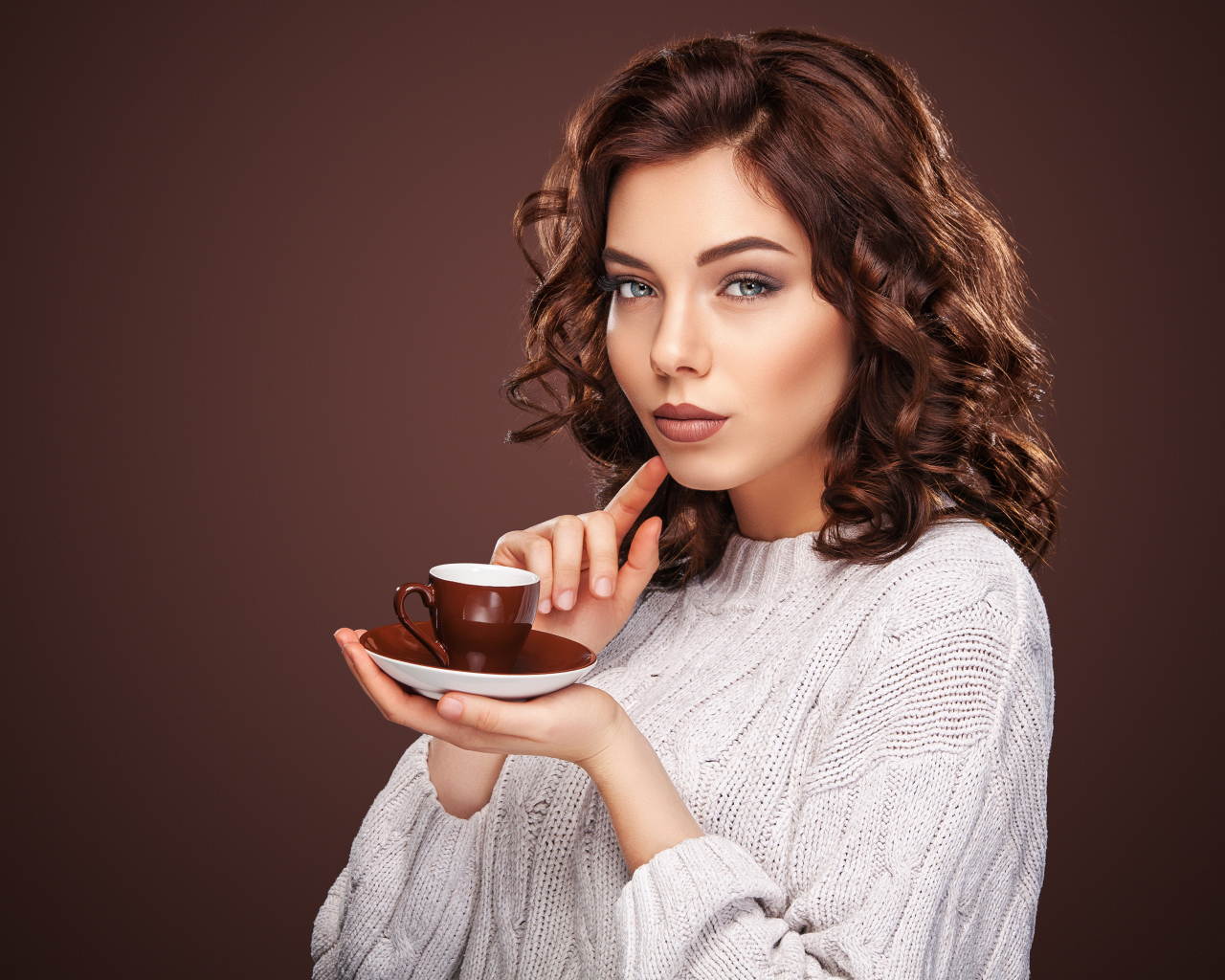 Красивая девушка в белом свитере с чашкой кофе