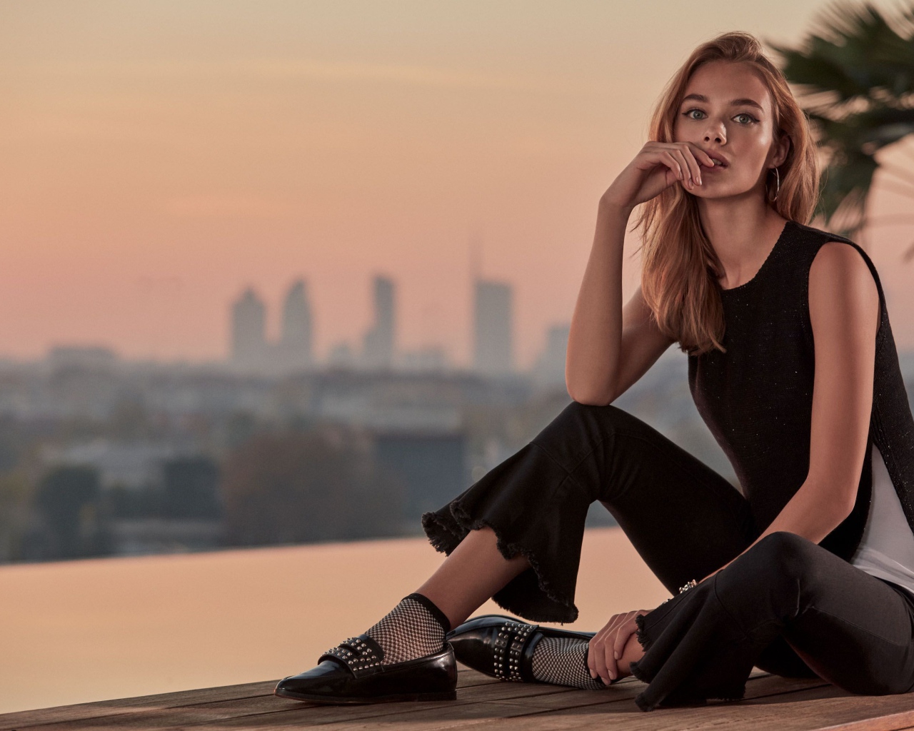 Красивая девушка в черном сидит  на мосту 