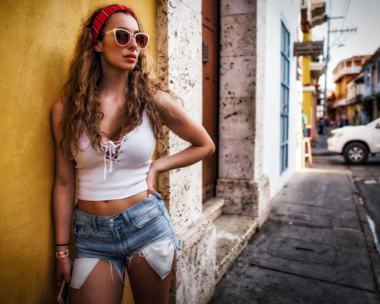 Красивая девушка в солнечных очках стоит у стены