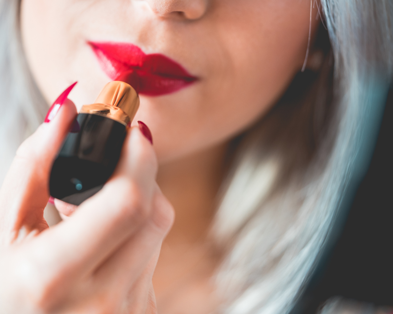 Красивая девушка красит губы красной помадой 