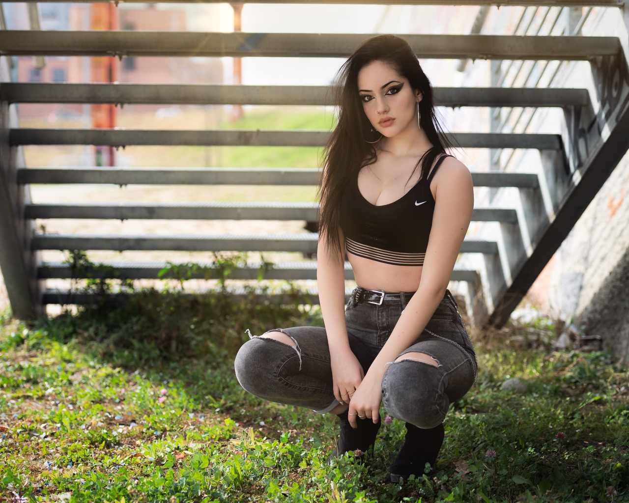 Красивая девушка сидит под лестницей 