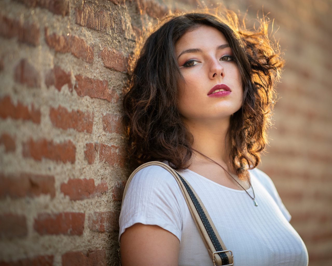 Красивая девушка стоит у стены 