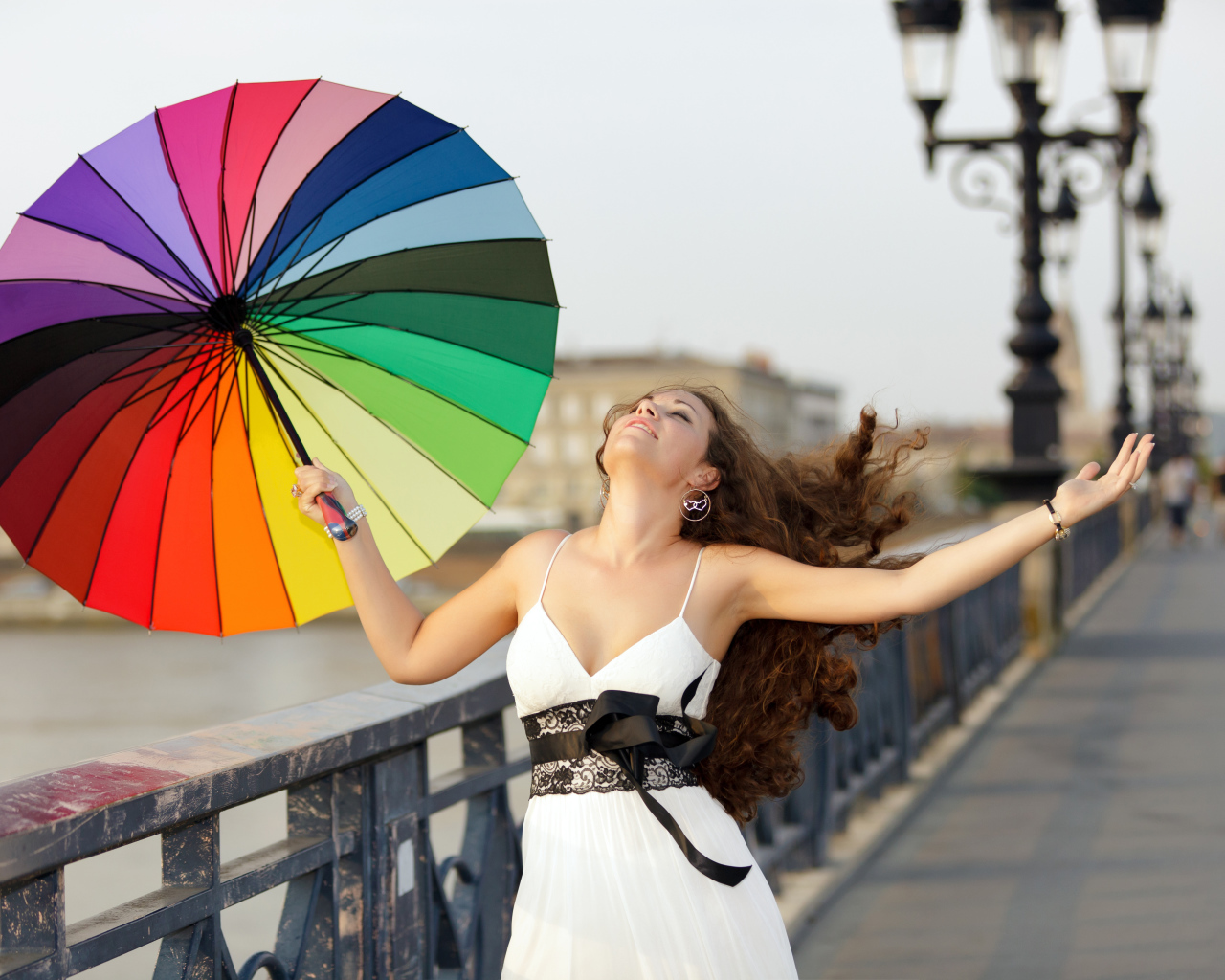 Красивая девушка идет по мосту с разноцветным зонтом