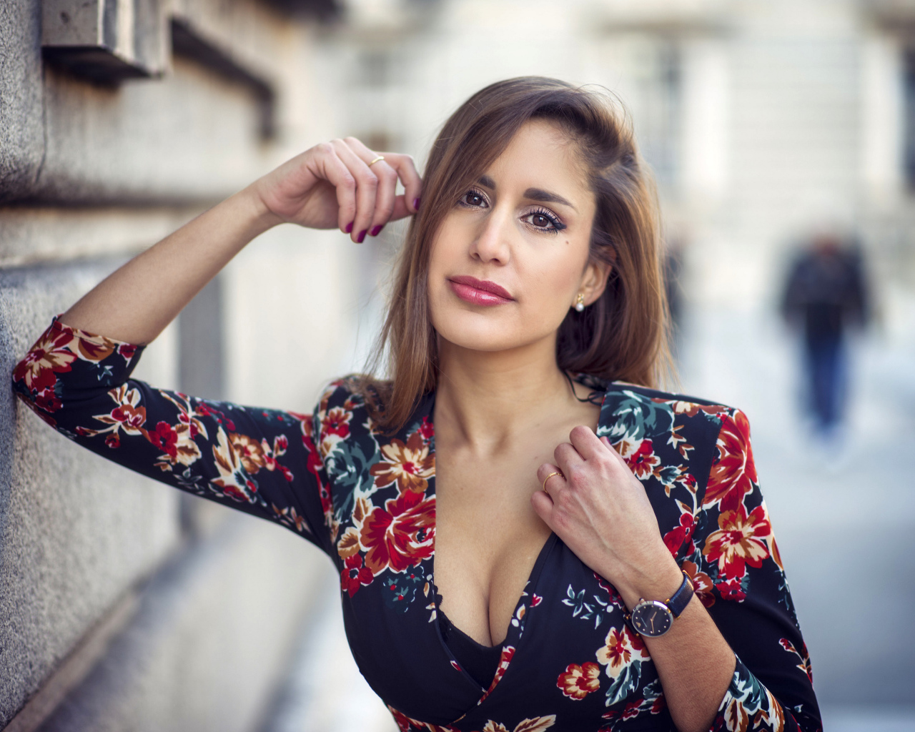 Красивая девушка с часами на руке стоит у стены