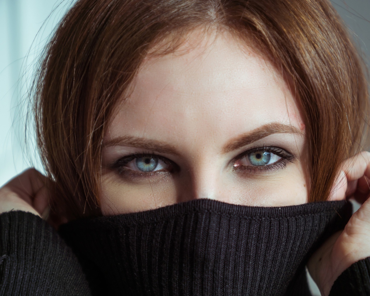 Красивая девушка с голубыми глазами закрыла лицо свитером 