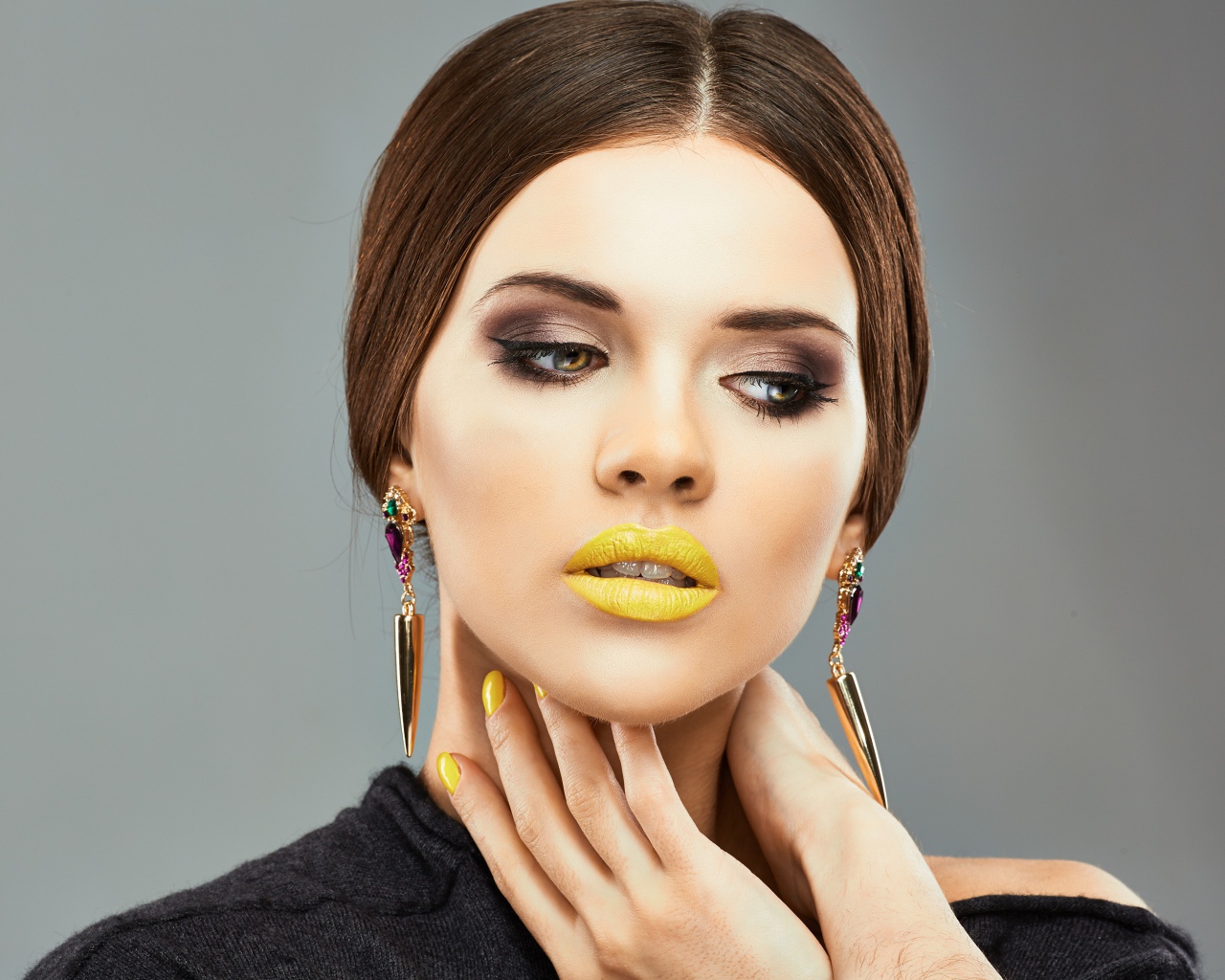 Красивая девушка с дорогими серьгами в ушах на сером фоне