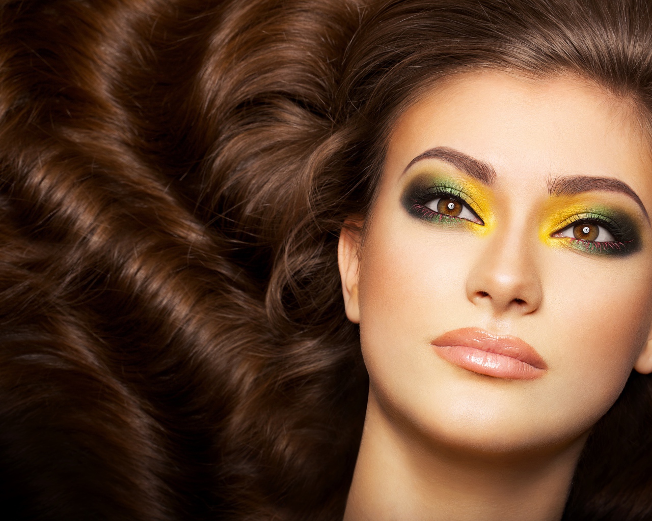 Красивая длинноволосая девушка с ярким макияжем на глазах 