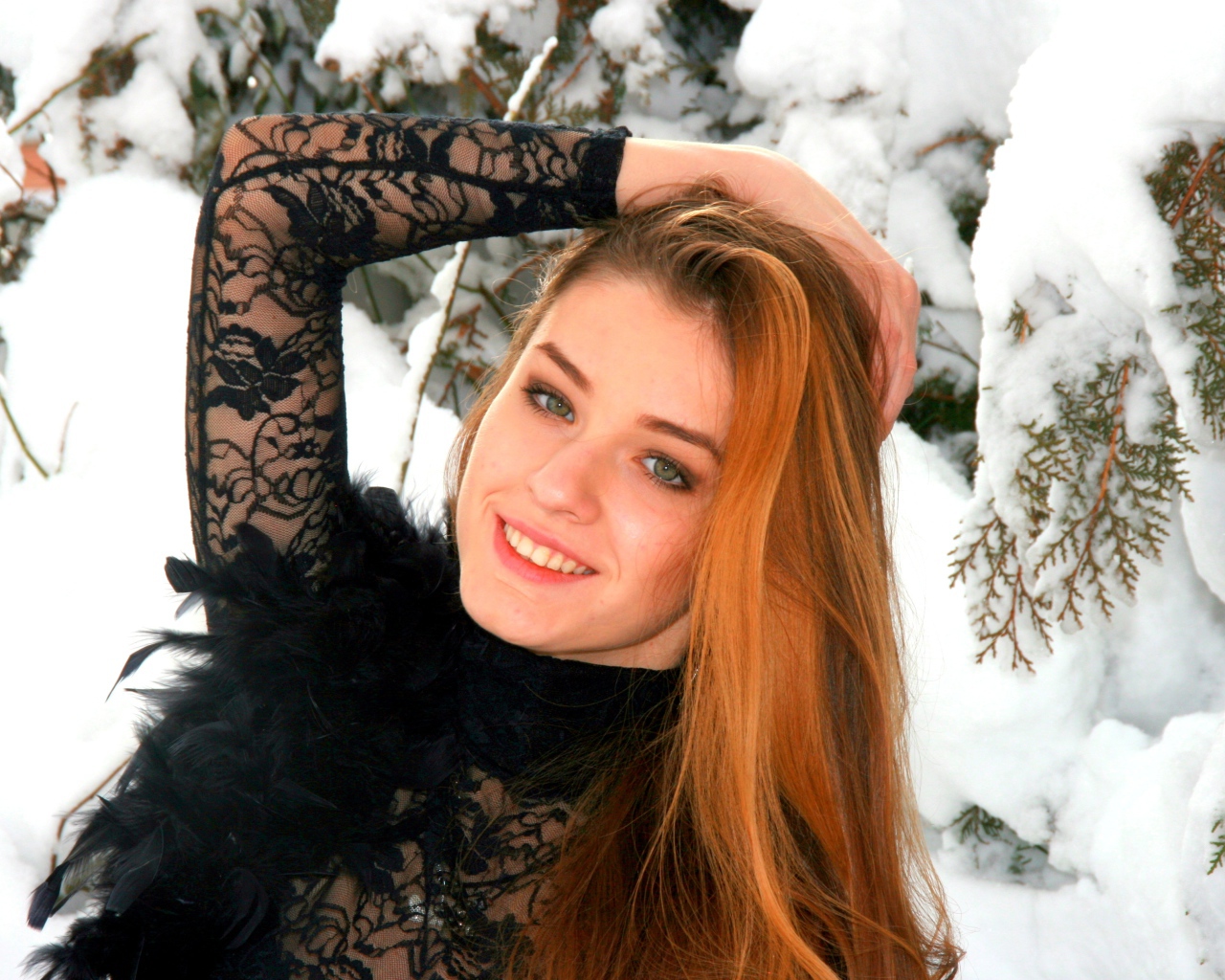 Красивая рыжеволосая девушка у заснеженной туи