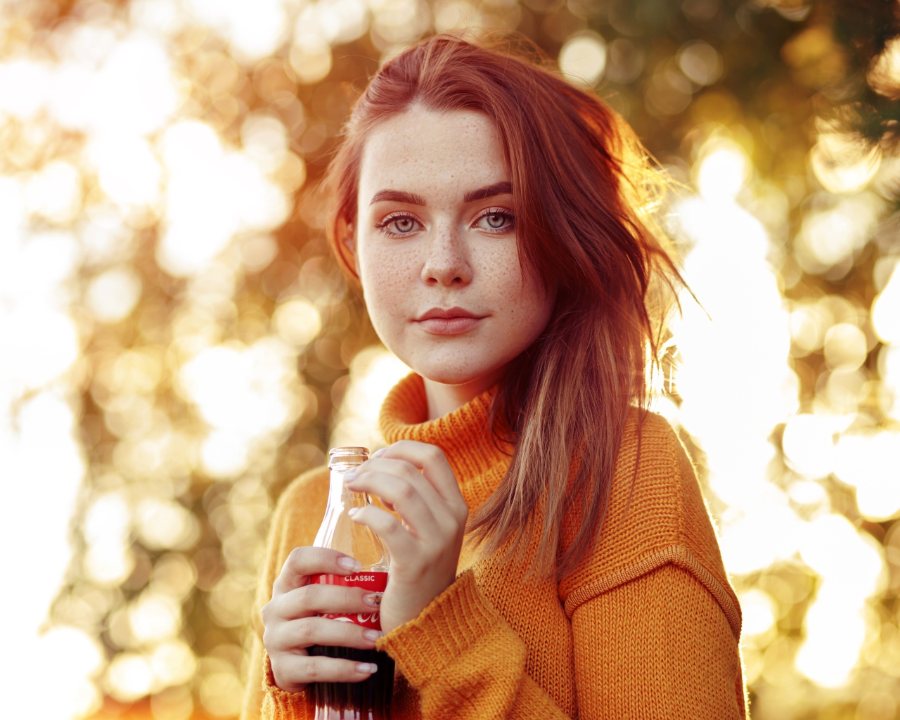 Красивая рыжеволосая девушка с бутылкой кока колы в руке 