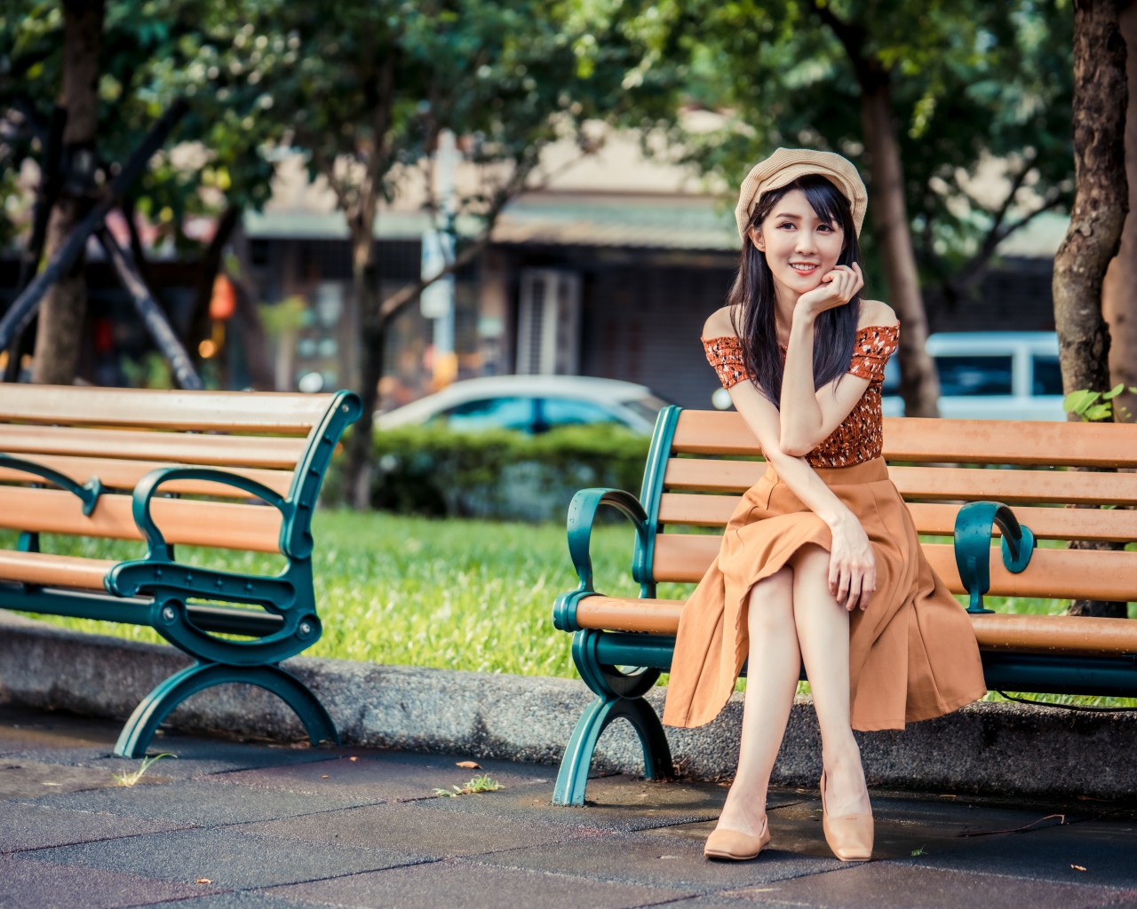 Красивая улыбающаяся азиатка сидит на лавке в парке