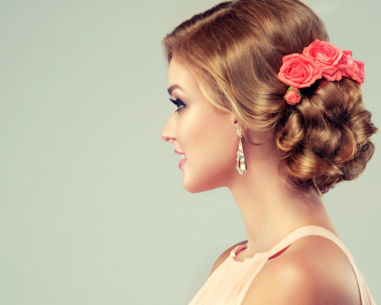 Красивая свадебная прическа у молодой девушки на сером фоне 