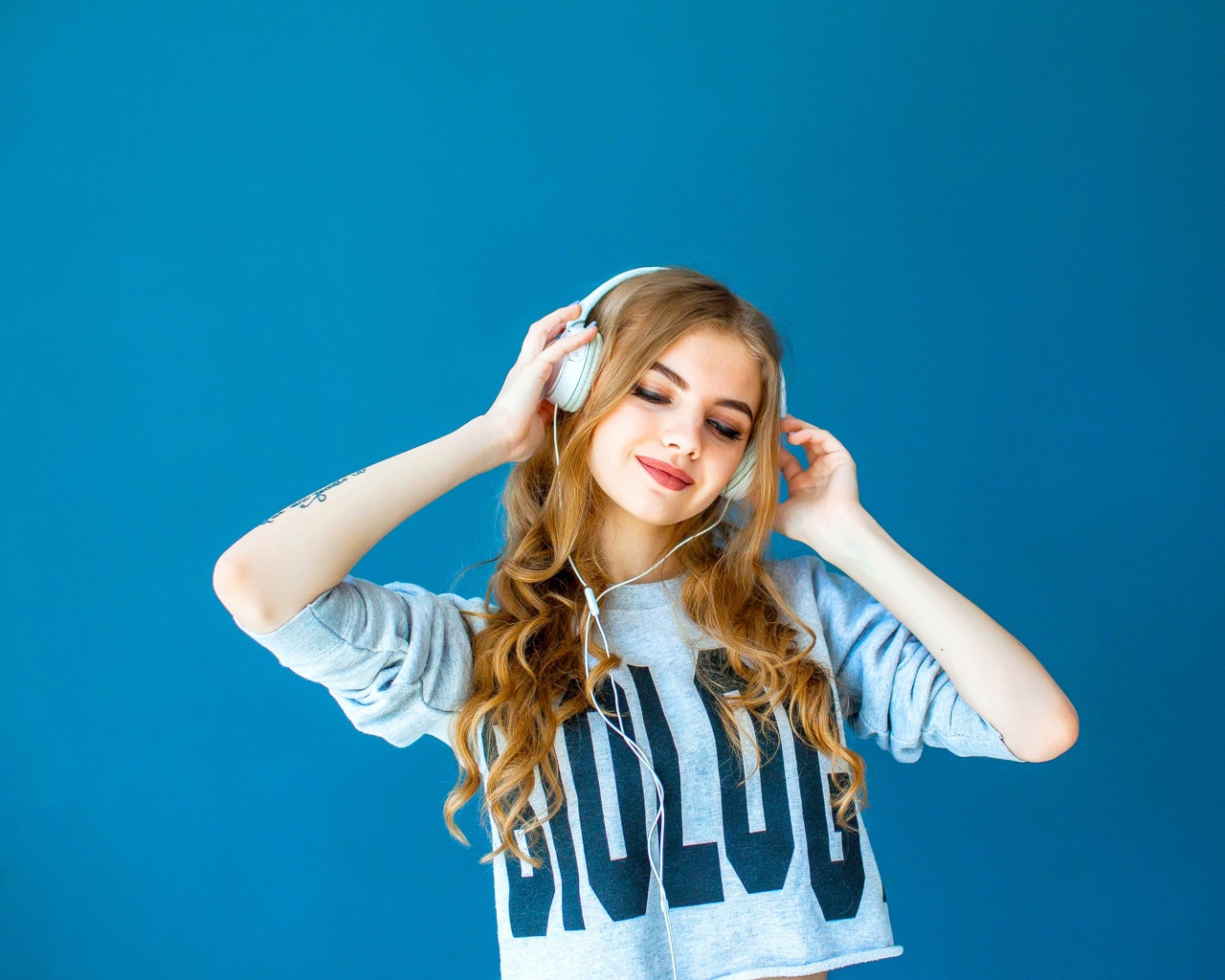 Красивая молодая девушка в наушниках на голубом фоне