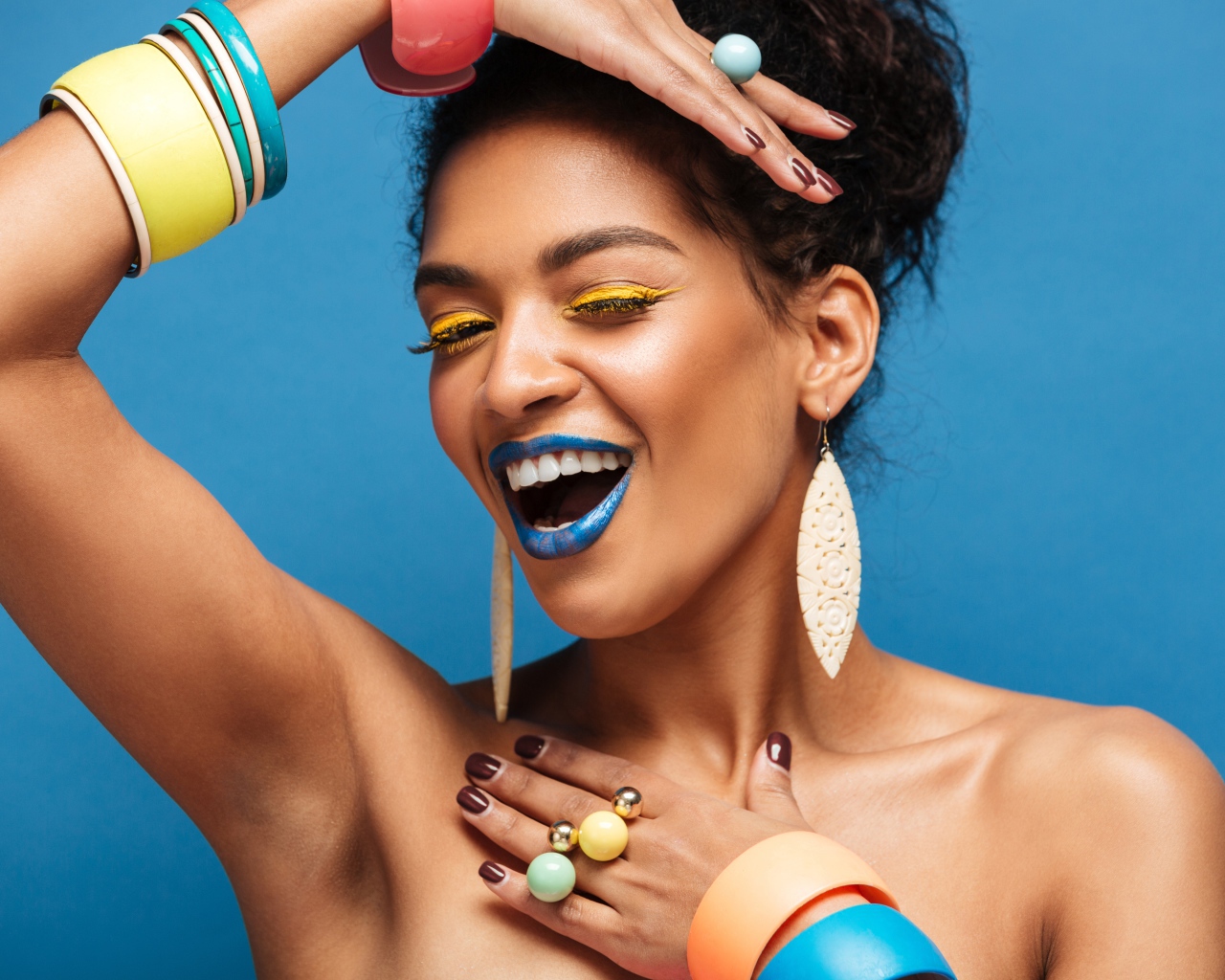 Красивая молодая девушка с ярким разноцветным макияжем на голубом фоне