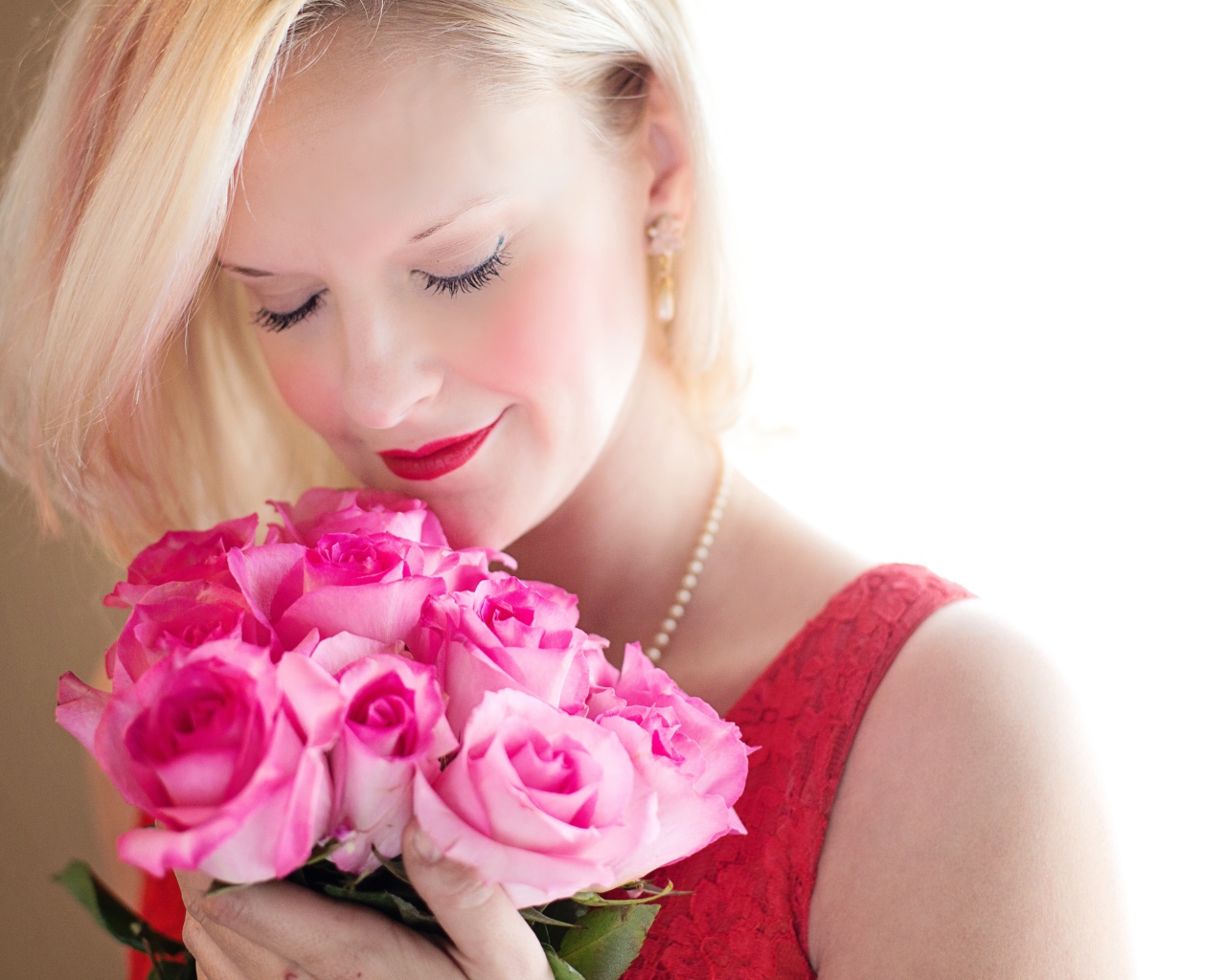 Блондинка с закрытыми глазами нюхает букет роз