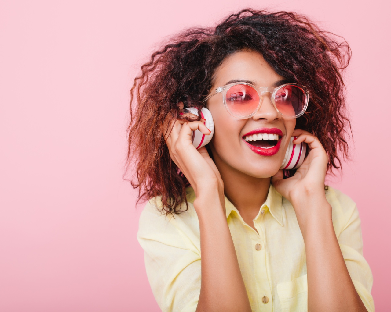 Яркая улыбающаяся девушка слушает музыку в наушниках 