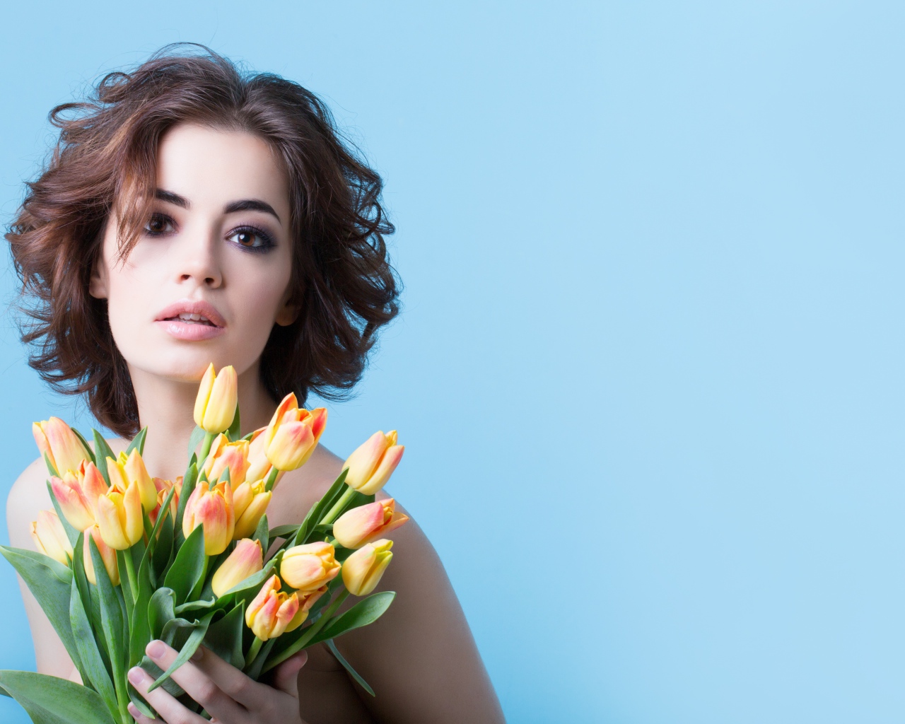Кареглазая шатенка с букетом тюльпанов на голубом фоне