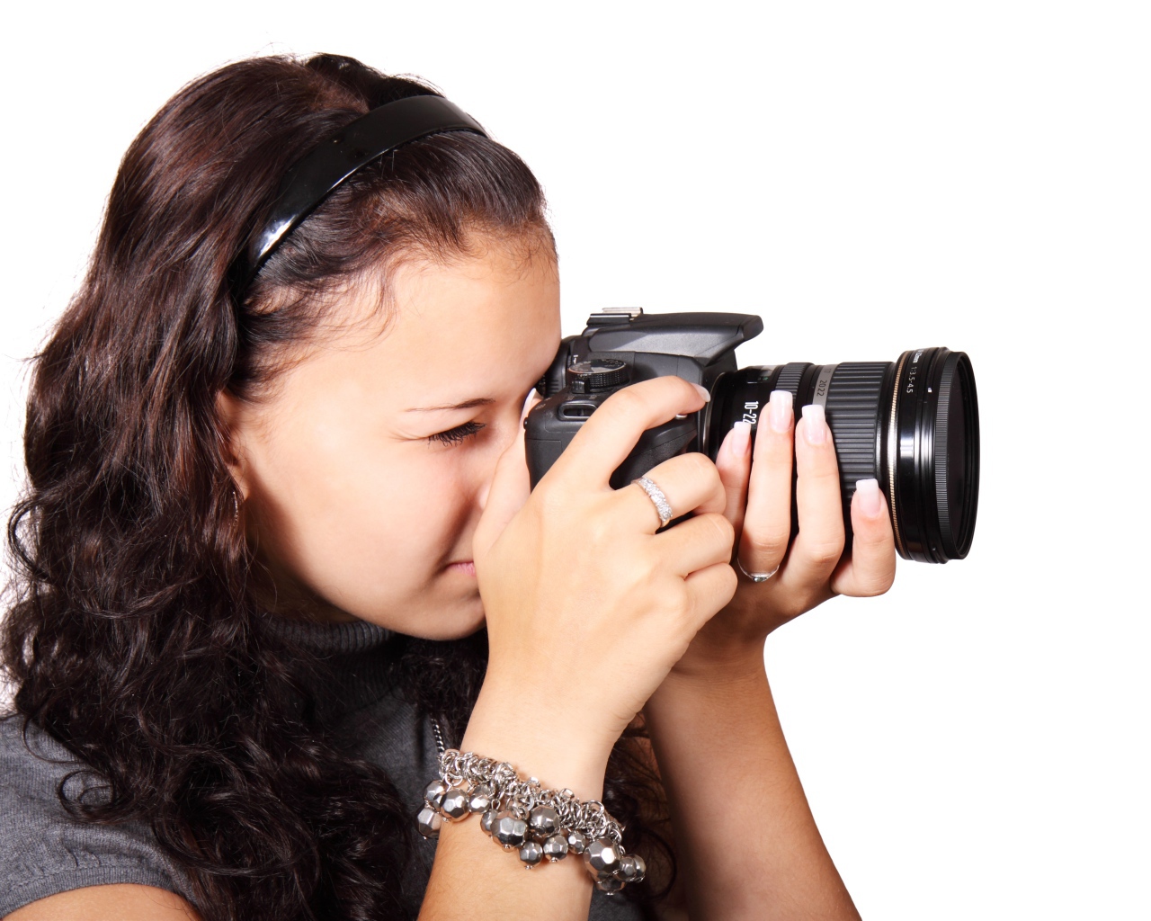 Молодая девушка шатенка с фотоаппаратом в руках на белом фоне