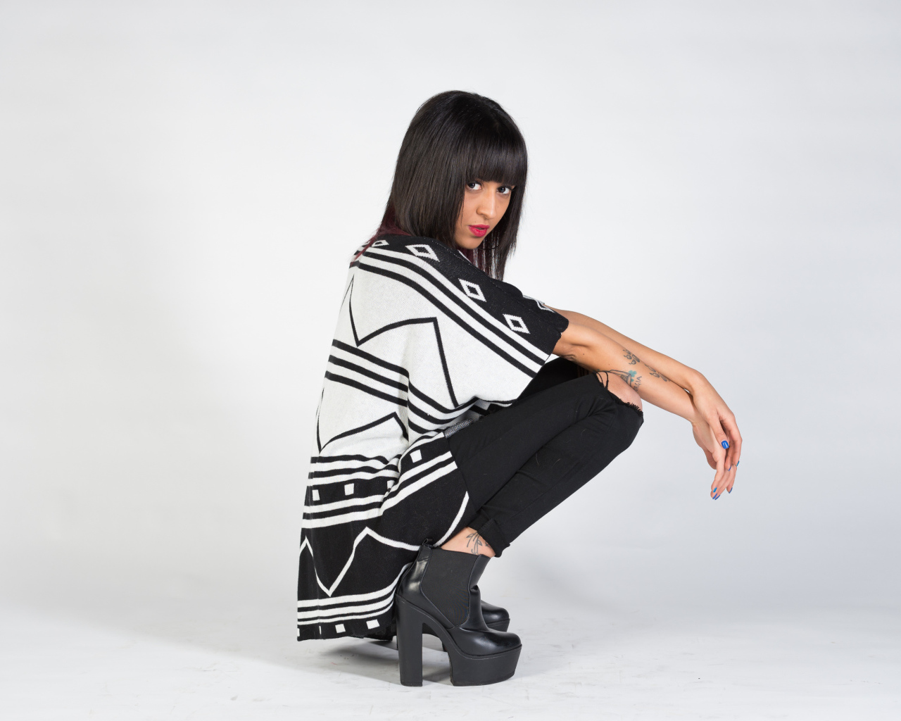 Брюнетка сидит на корточках 