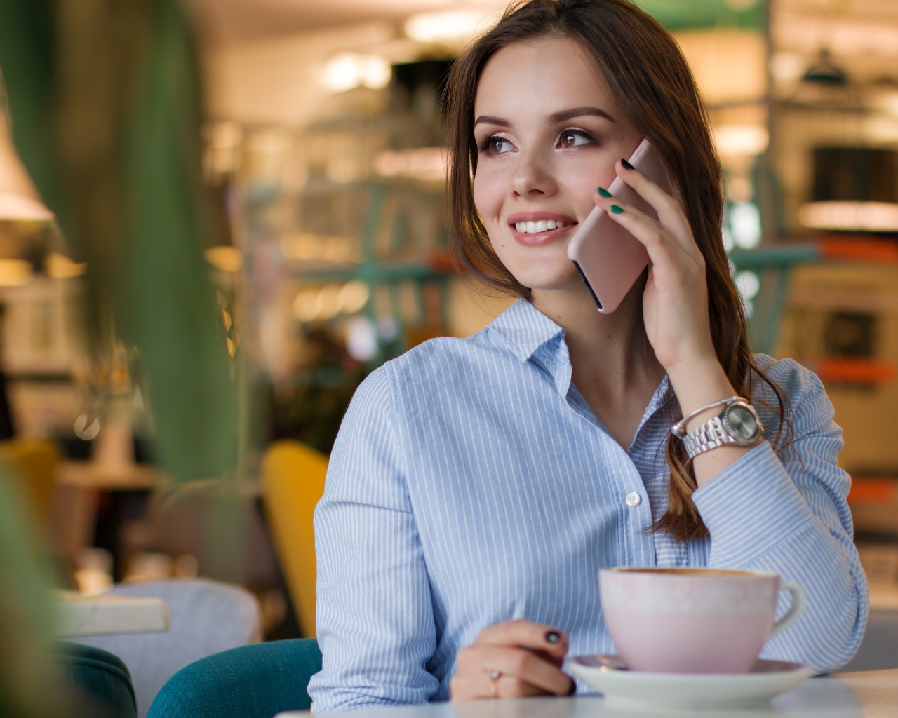 Деловая девушка в рубашке разговаривает в кафе по телефону