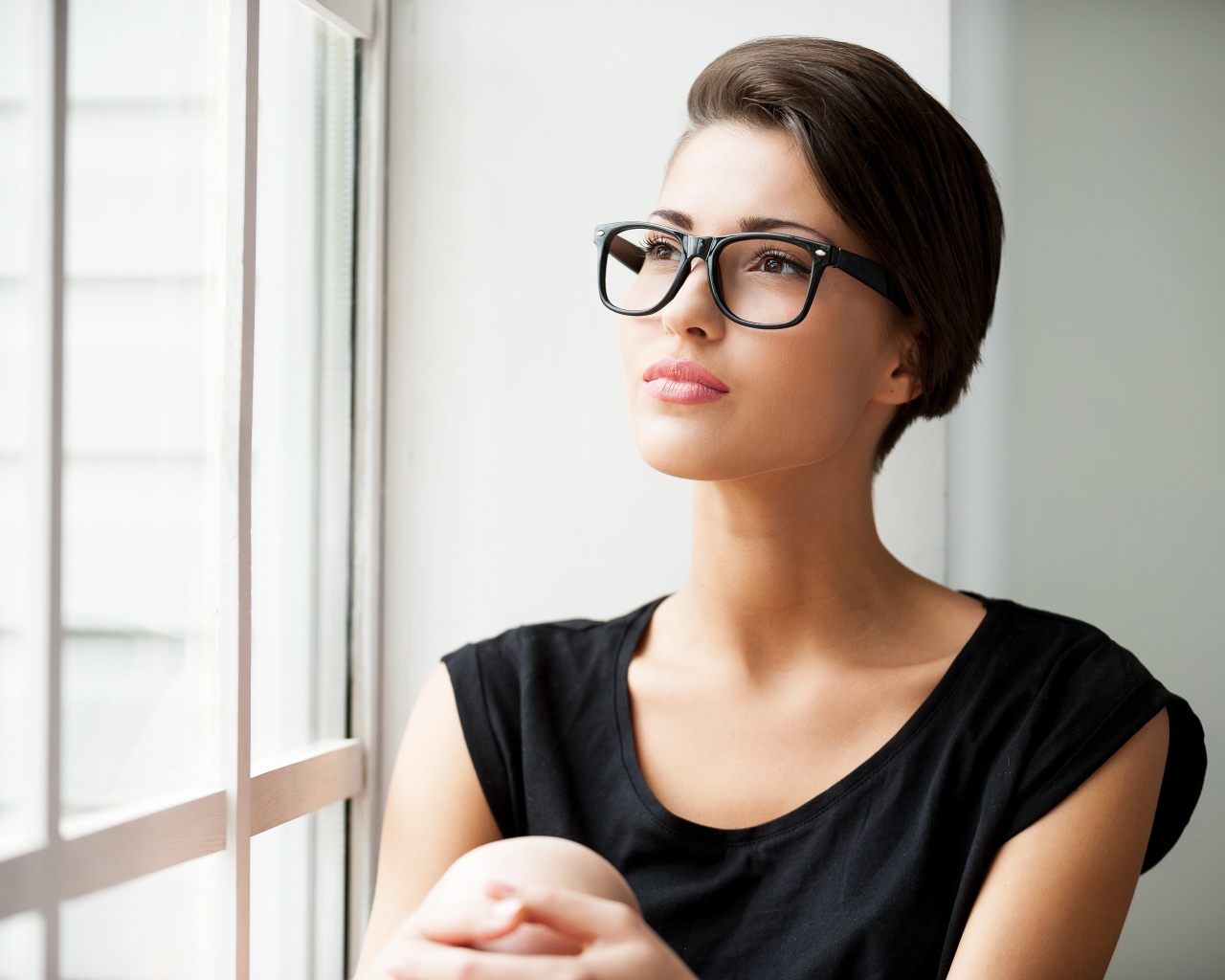 Деловая девушка в очках сидит у окна 