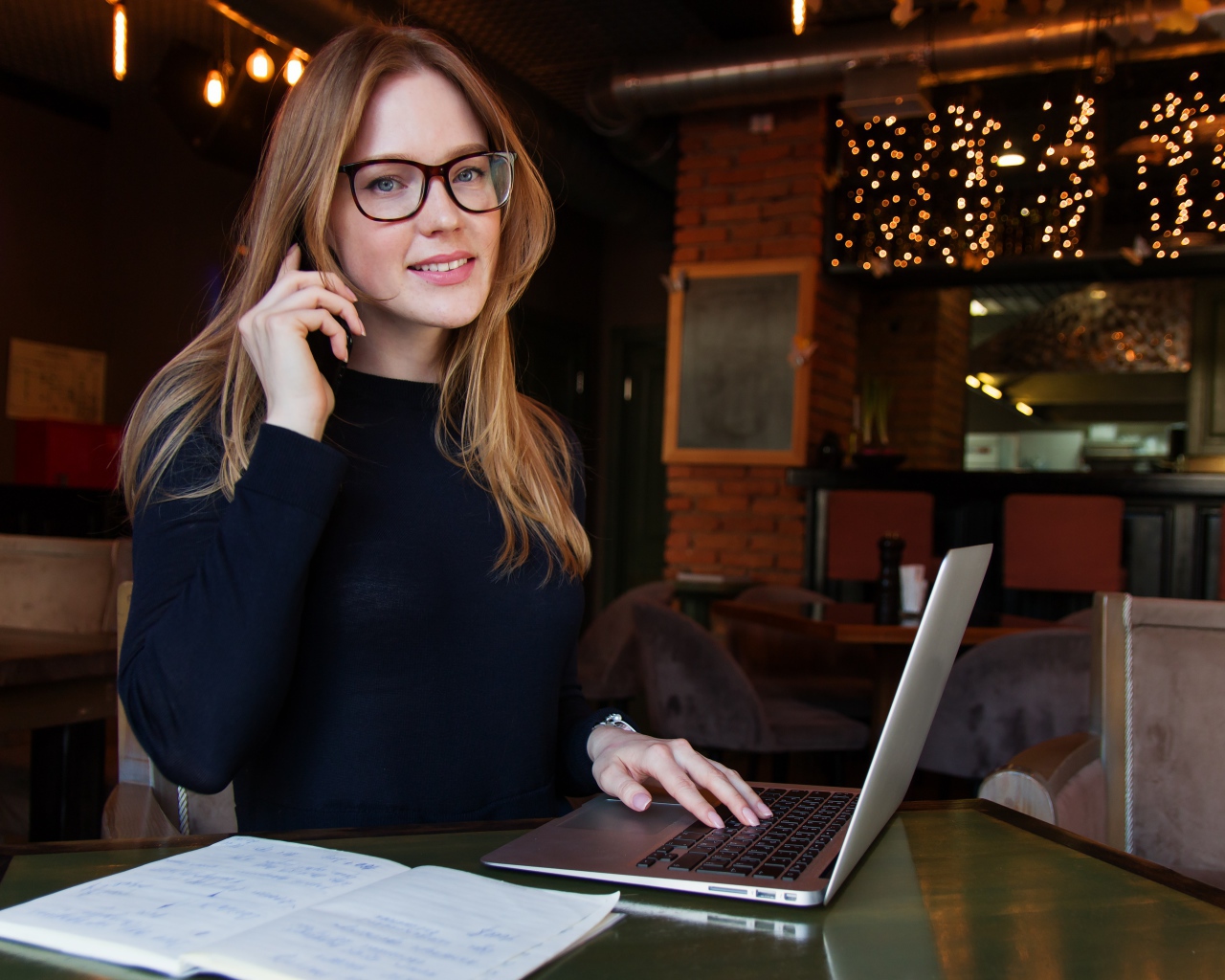 Деловая девушка в очках сидит с кафе с ноутбуком